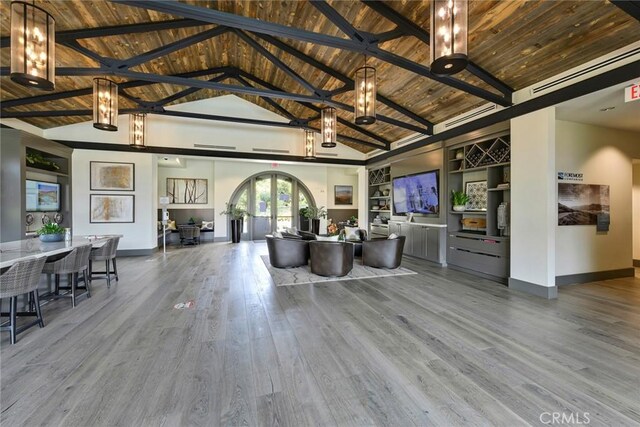 unfurnished living room with wood-type flooring, french doors, beam ceiling, high vaulted ceiling, and wooden ceiling