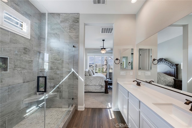 bathroom featuring ceiling fan, vanity, wood-type flooring, and a tile shower