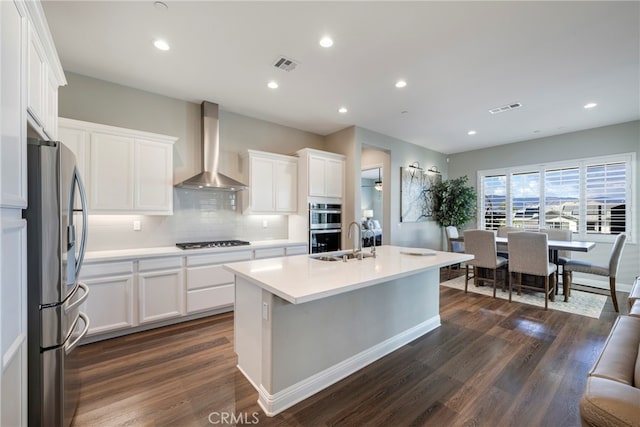 kitchen with stainless steel appliances, wall chimney exhaust hood, white cabinets, and dark wood-type flooring