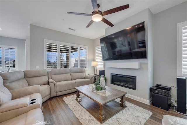 24185 Sprout Dr, Corona, CA 92883 - living room featuring baseboards, visible vents, a ceiling fan, a glass covered fireplace, and wood finished floors