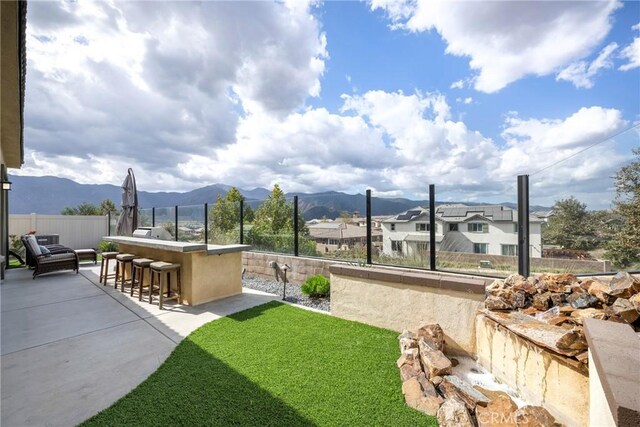 view of home's community with a mountain view, a lawn, a patio, and a bar