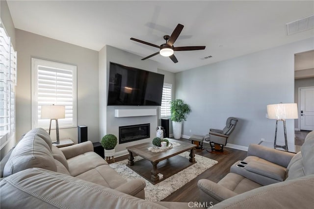 24185 Sprout Dr, Corona, CA 92883 - living area featuring a ceiling fan, wood finished floors, a glass covered fireplace, baseboards, and visible vents