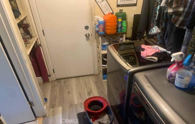 laundry area with washing machine and clothes dryer and light hardwood / wood-style floors