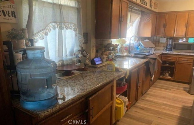 kitchen featuring tasteful backsplash, light hardwood / wood-style flooring, a wealth of natural light, and light stone counters