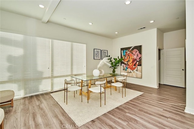 dining room with light hardwood / wood-style floors and beam ceiling