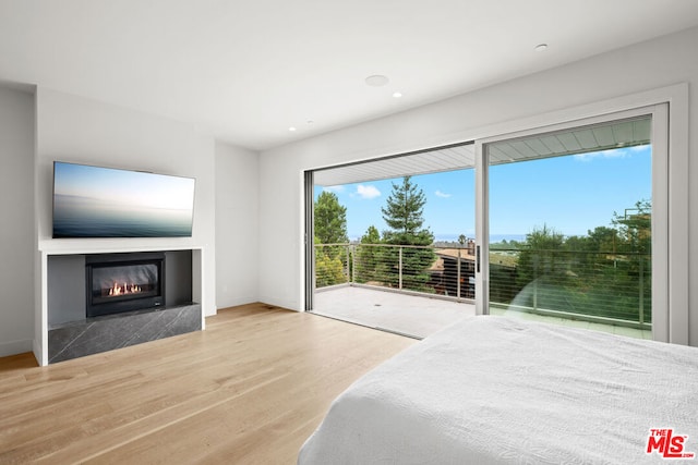 bedroom with multiple windows, access to outside, and light wood-type flooring