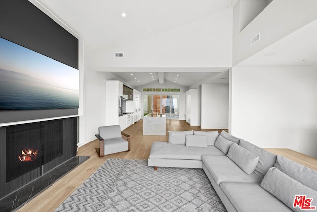 living room featuring light hardwood / wood-style flooring and lofted ceiling with beams