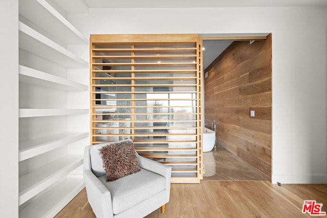 living area featuring hardwood / wood-style floors and wooden walls