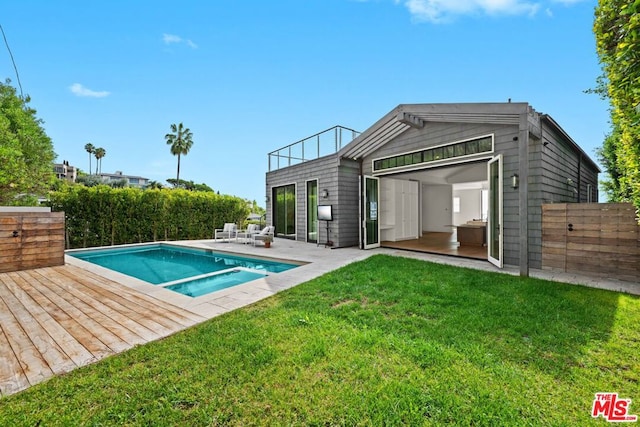 rear view of house featuring a fenced in pool, a patio area, an outbuilding, and a lawn