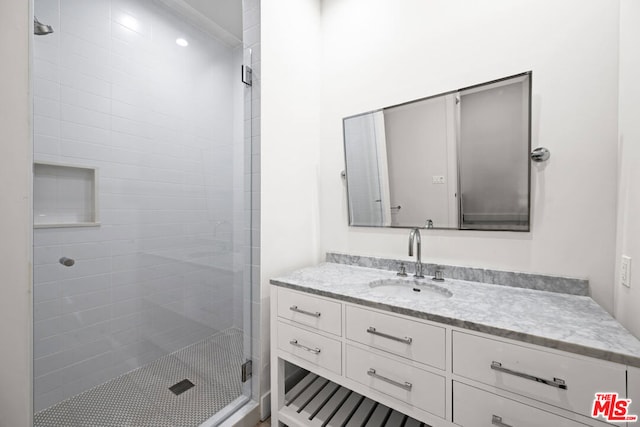 bathroom featuring a shower with shower door and vanity