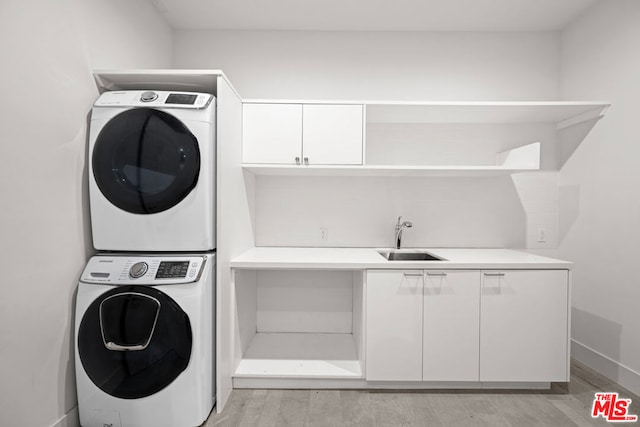 laundry room with stacked washer / dryer, light wood-type flooring, sink, and cabinets