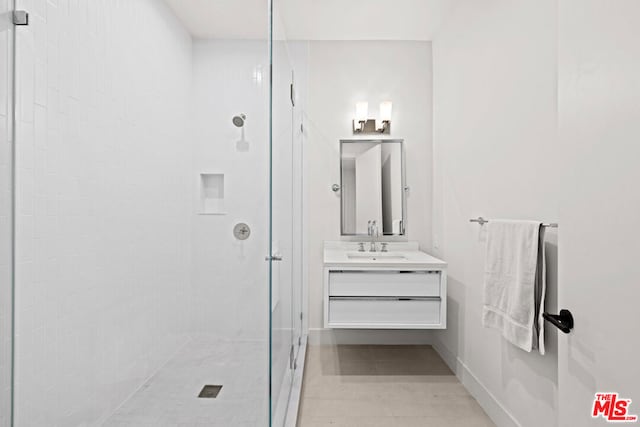 bathroom with tiled shower and vanity