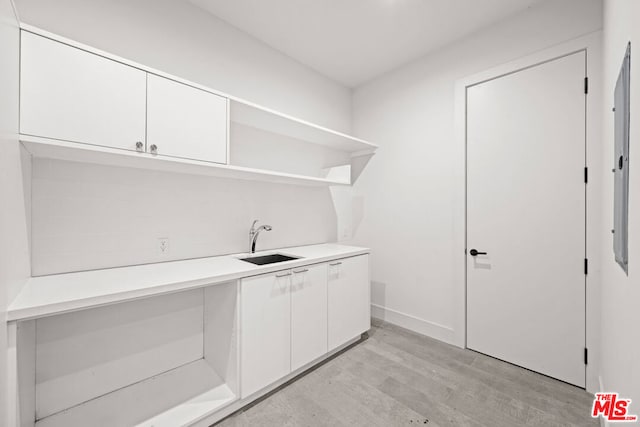 clothes washing area with sink and light hardwood / wood-style flooring