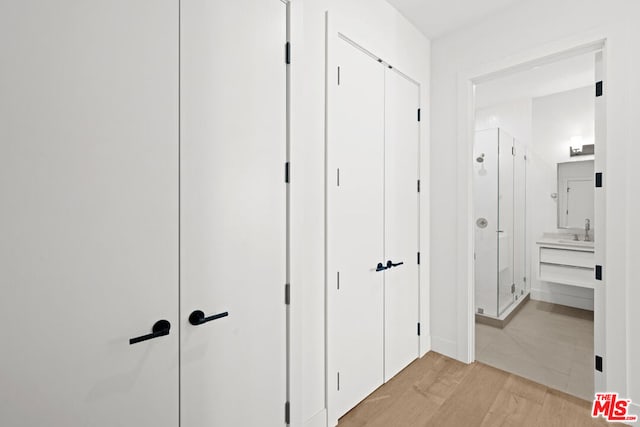 corridor with sink and light wood-type flooring