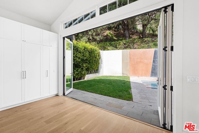 doorway to outside featuring vaulted ceiling and light wood-type flooring