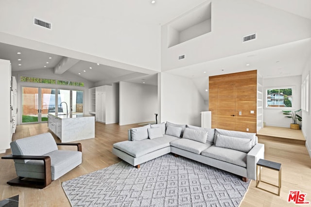 living room with a wealth of natural light, beam ceiling, light hardwood / wood-style flooring, and high vaulted ceiling