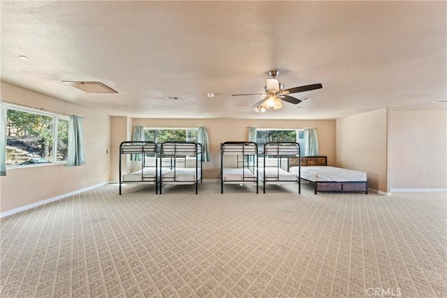 carpeted bedroom with multiple windows, ceiling fan, and a textured ceiling