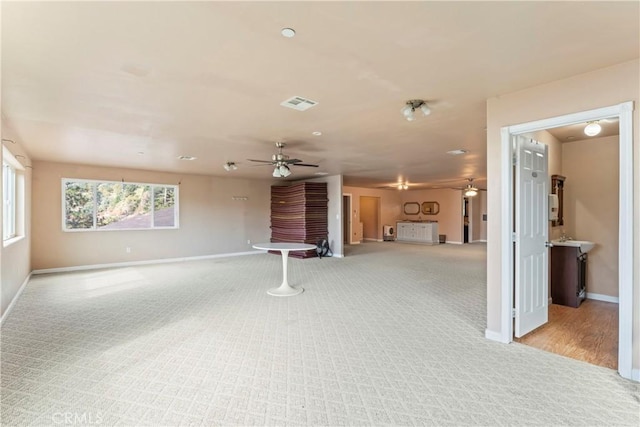 unfurnished living room featuring light carpet and ceiling fan