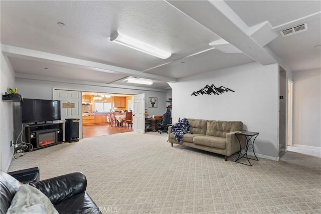 living room featuring carpet, beam ceiling, and a textured ceiling