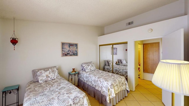 tiled bedroom with lofted ceiling, a closet, and a textured ceiling