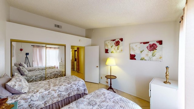 bedroom with light tile patterned floors, a textured ceiling, and a closet