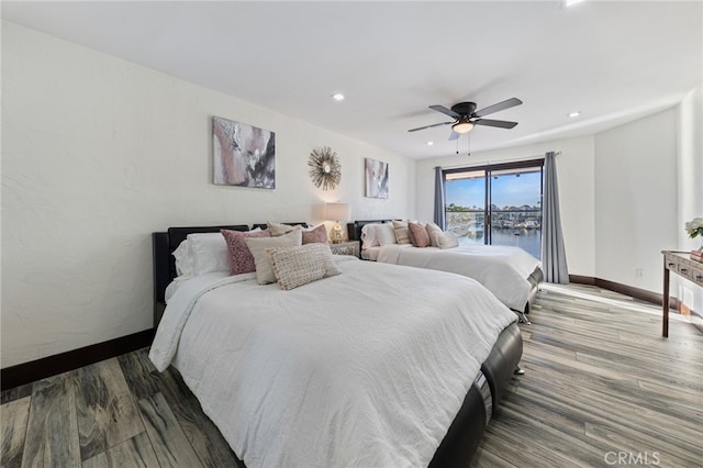 bedroom featuring ceiling fan, a water view, and dark wood-type flooring