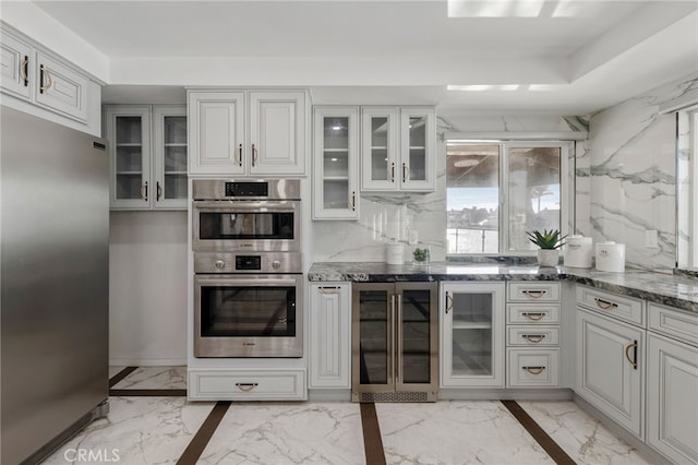 kitchen featuring white cabinets, wine cooler, dark stone countertops, and appliances with stainless steel finishes