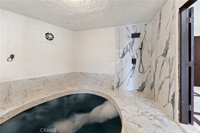 bathroom with a tile shower and a textured ceiling