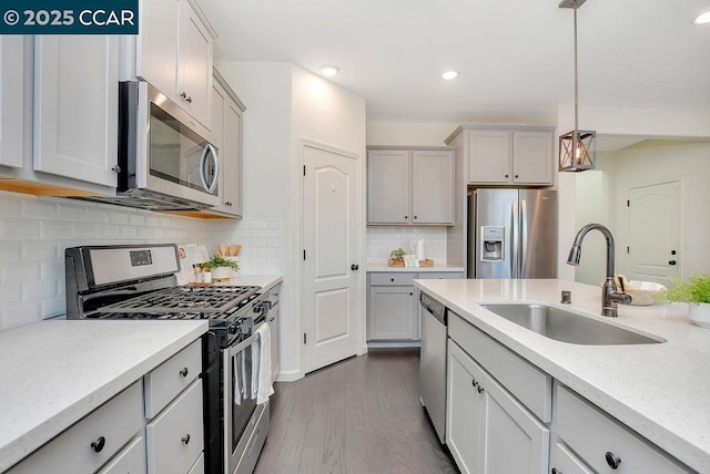 kitchen featuring pendant lighting, sink, dark wood-type flooring, appliances with stainless steel finishes, and tasteful backsplash