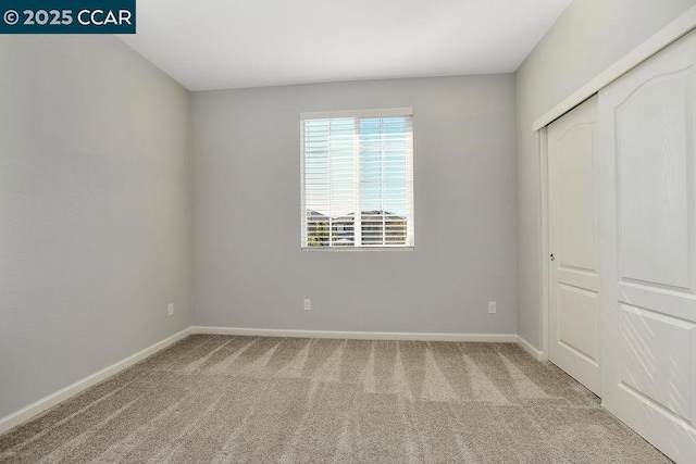 unfurnished bedroom featuring light carpet and a closet