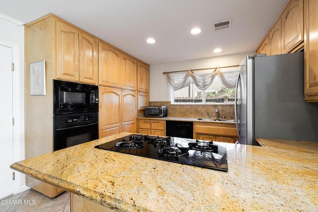 kitchen featuring light tile patterned flooring, sink, decorative backsplash, light stone counters, and black appliances