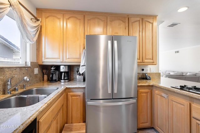 kitchen with sink, decorative backsplash, stainless steel refrigerator, and light brown cabinets