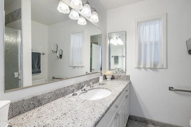 bathroom featuring tile patterned flooring, vanity, toilet, and walk in shower