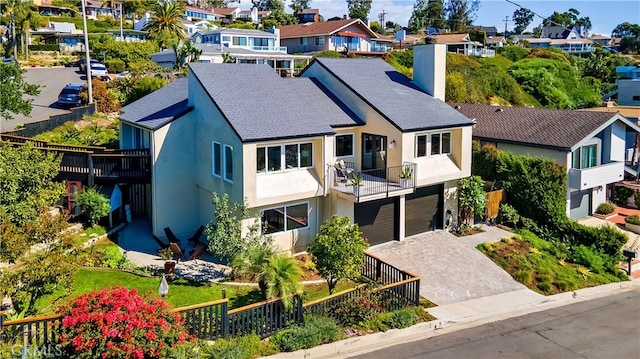 view of front of property featuring a garage, a chimney, a residential view, decorative driveway, and stucco siding