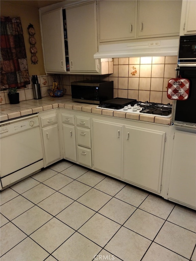 kitchen with backsplash, white cabinetry, light tile patterned flooring, tile counters, and white appliances