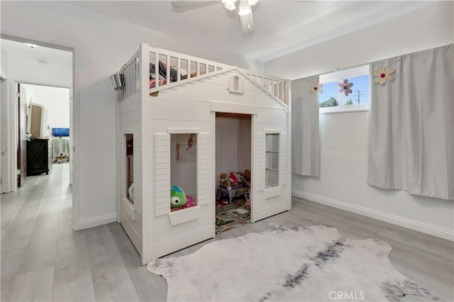 unfurnished bedroom with hardwood / wood-style floors, a crib, and ceiling fan