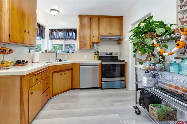 kitchen featuring appliances with stainless steel finishes, tasteful backsplash, sink, and light hardwood / wood-style floors