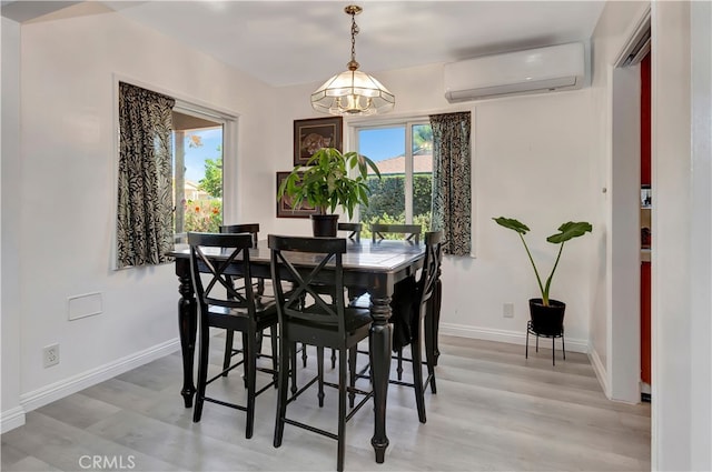 dining area with a wealth of natural light, a wall mounted AC, and light hardwood / wood-style floors