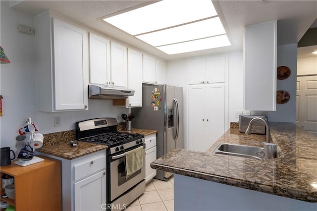 kitchen with appliances with stainless steel finishes, sink, white cabinets, light tile patterned floors, and kitchen peninsula