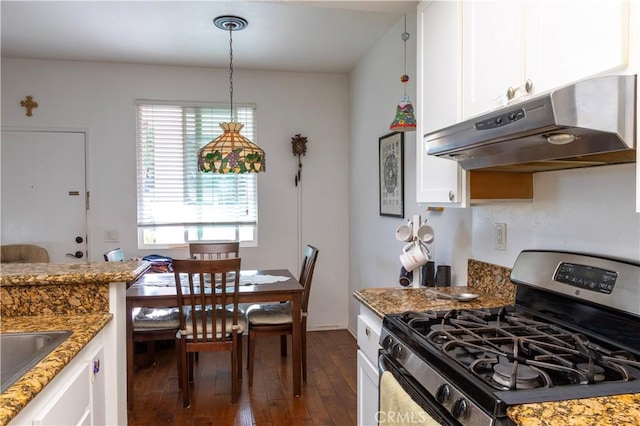 kitchen featuring white cabinets, pendant lighting, stainless steel gas range, and dark stone counters