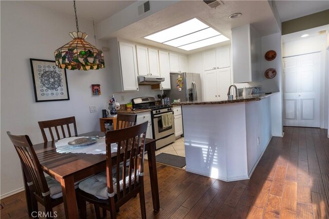 kitchen with kitchen peninsula, light hardwood / wood-style flooring, white cabinets, and stainless steel appliances