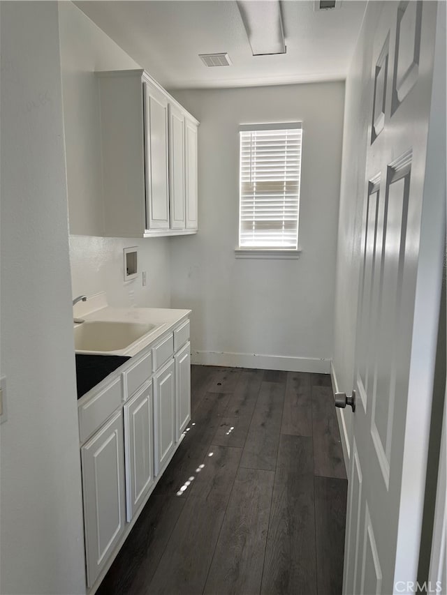 clothes washing area featuring cabinets, sink, washer hookup, and dark hardwood / wood-style flooring