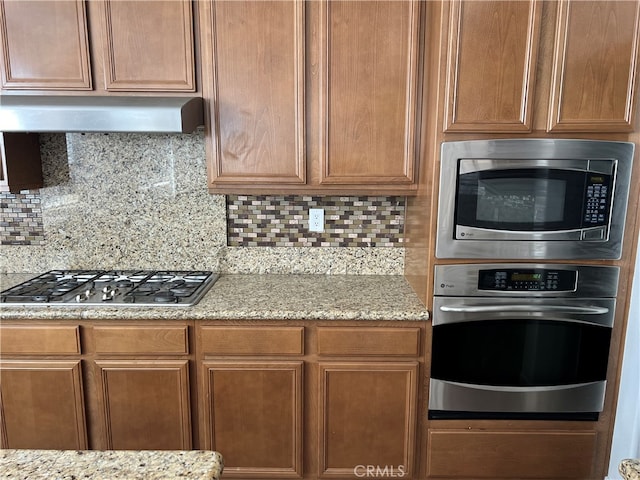 kitchen with stainless steel appliances, light stone countertops, and tasteful backsplash