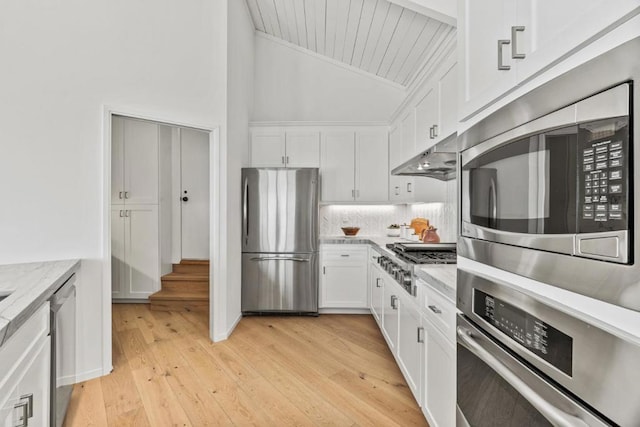 kitchen featuring white cabinets, light hardwood / wood-style floors, vaulted ceiling, and appliances with stainless steel finishes