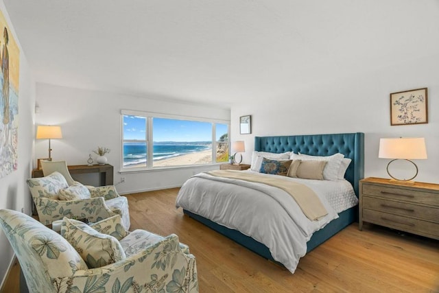 bedroom featuring a water view and light wood-type flooring