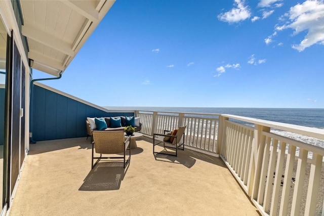 balcony with outdoor lounge area, a water view, and a beach view