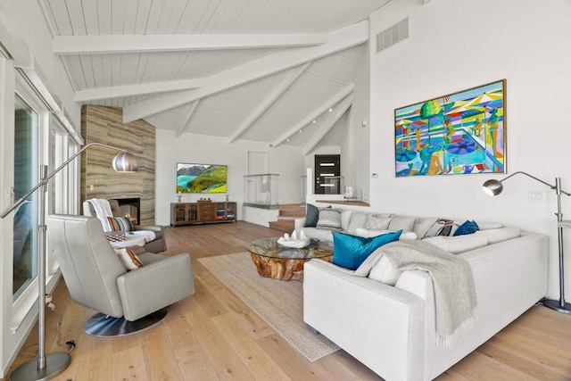 living room with a large fireplace, lofted ceiling with beams, and light hardwood / wood-style floors