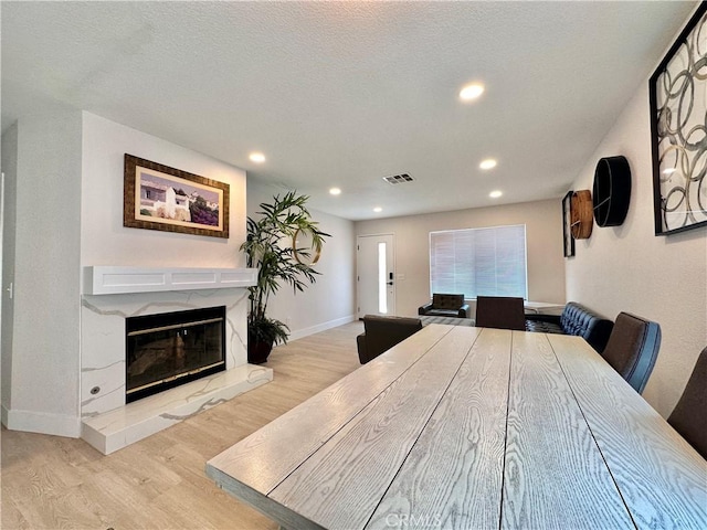 dining area with a textured ceiling and light wood-type flooring