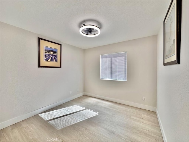 empty room with light hardwood / wood-style floors and a textured ceiling