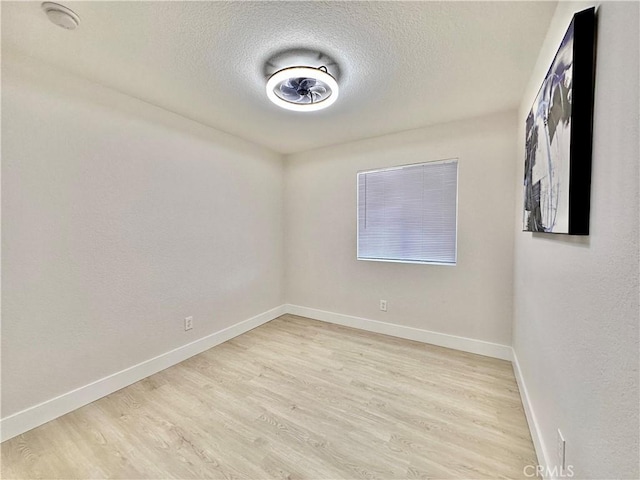 spare room with light wood-type flooring and a textured ceiling